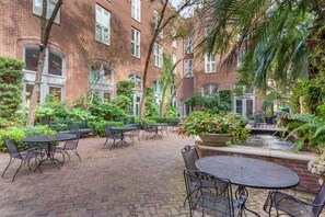 A courtyard with brick buildings, outdoor tables and chairs, a small water feature, and lush greenery. - Church Street Inn Historic Charleston, Ascend Collection Hotel (Charleston)
