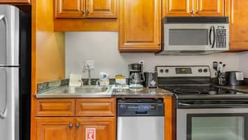A kitchen with wooden cabinets, a stainless steel refrigerator, a microwave, a stove, and a dishwasher.