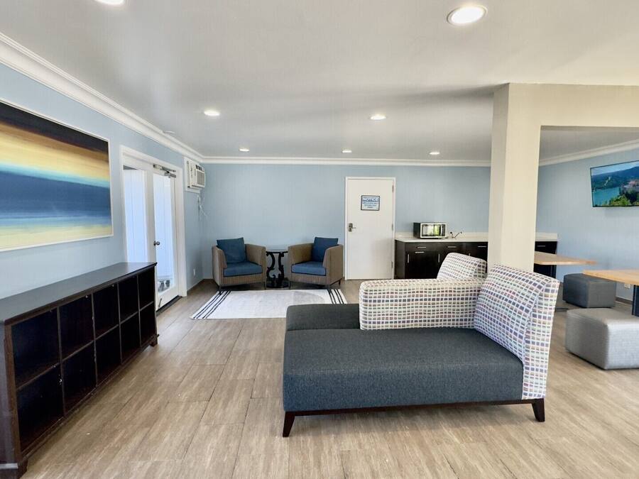 Uma sala de estar moderna com um sofá, cadeiras, uma televisão e um quadro na parede.