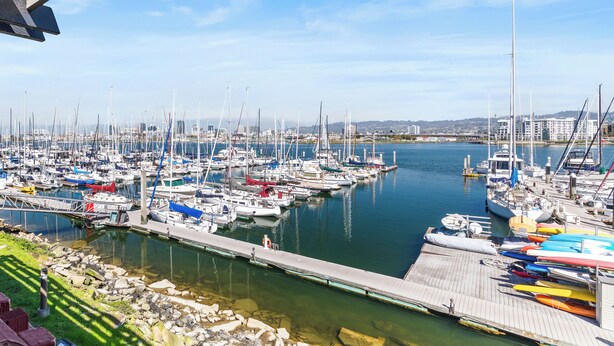 Un puerto deportivo con numerosas embarcaciones amarradas, un muelle y cielo despejado.