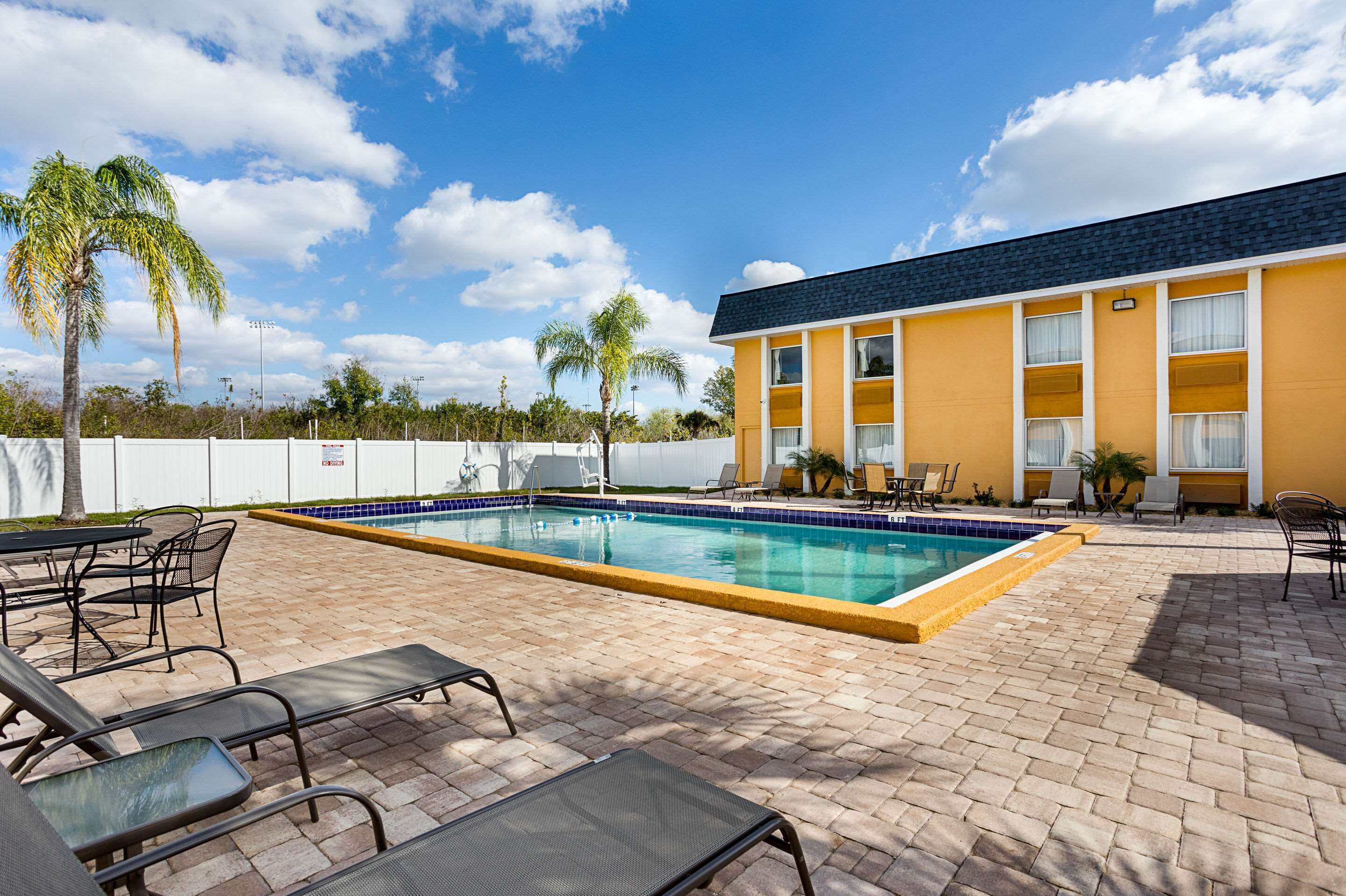 A swimming pool with lounge chairs and a building with a yellow facade.