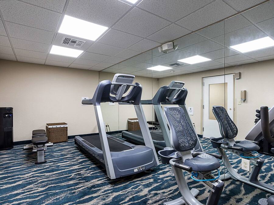 A hotel fitness room with treadmills, exercise bikes, and a mirrored wall.