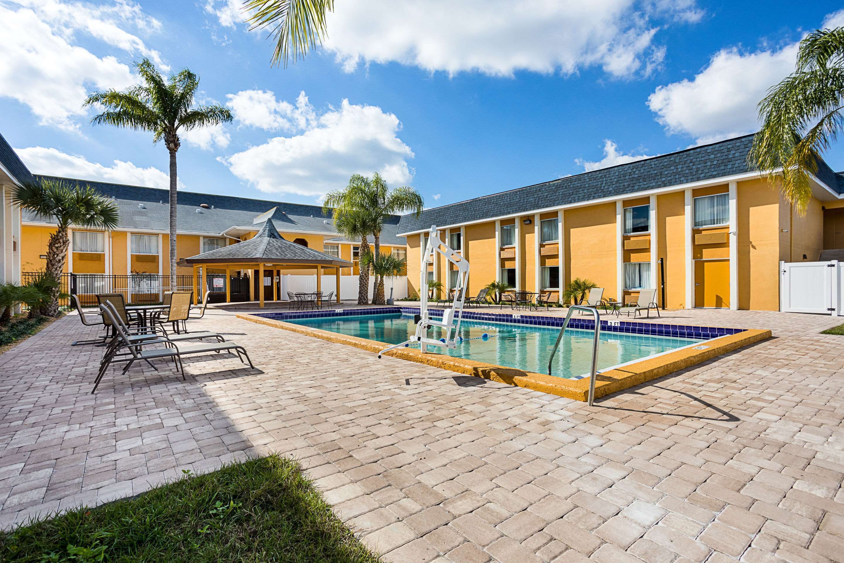 Un hôtel doté d’une piscine, d’un espace extérieur aménagé et de palmiers.