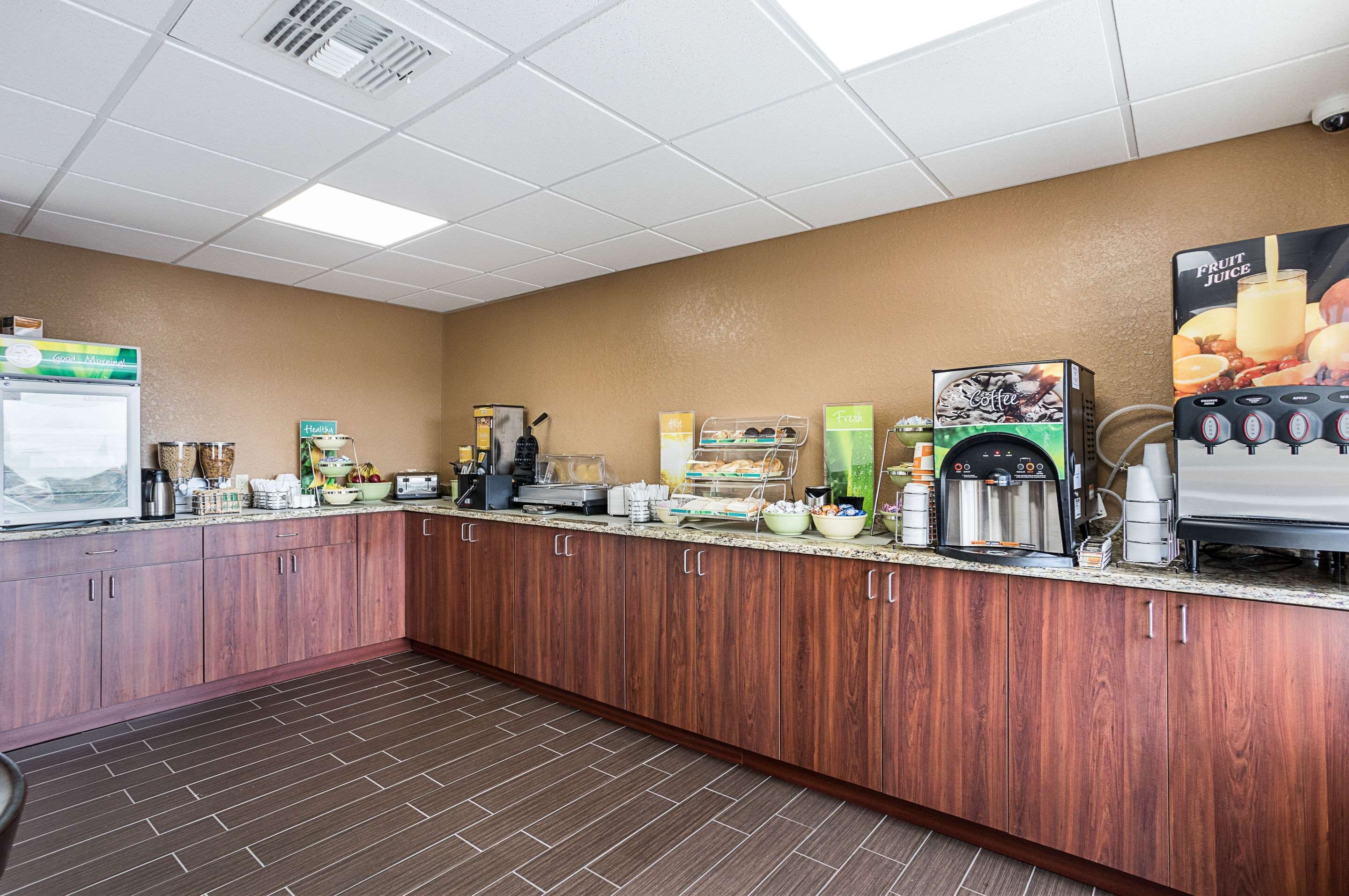 A self-service breakfast bar with various food and beverage options, including a coffee machine and a fruit juice dispenser.