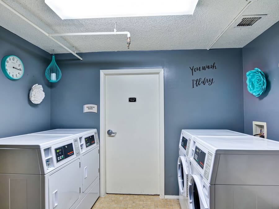 Un lavadero con dos lavadoras, un reloj y detalles decorativos en la pared.