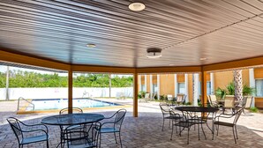 An outdoor pool area with a covered patio, seating arrangements, and a view of the pool. - Quality Inn & Suites Heritage Park (Kissimmee)