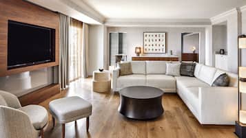 A modern living room with a large flat-screen TV, a sectional sofa, a round coffee table, and a sideboard.