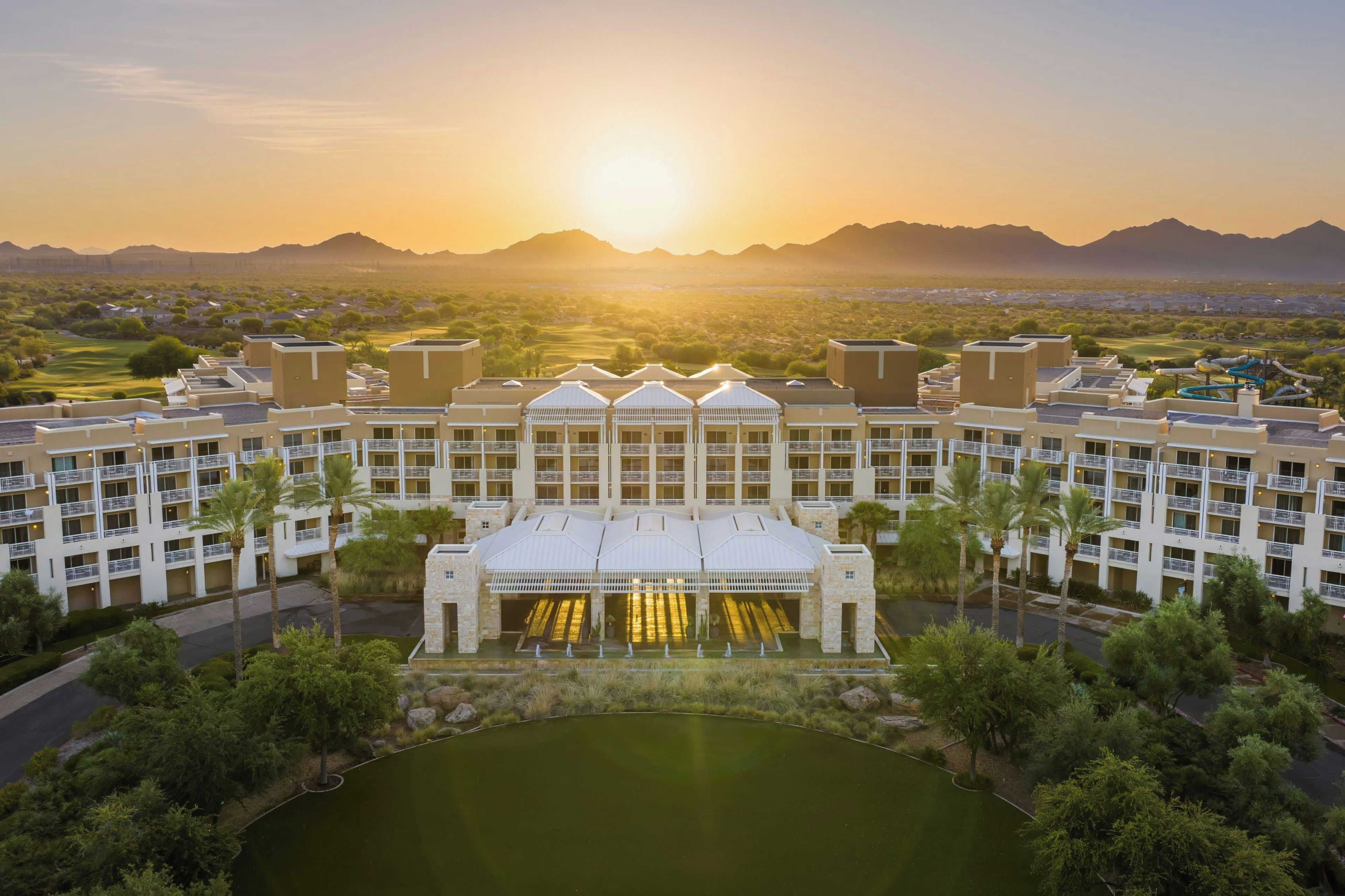 A hotel with a central courtyard, multiple floors, and a view of the surrounding landscape.