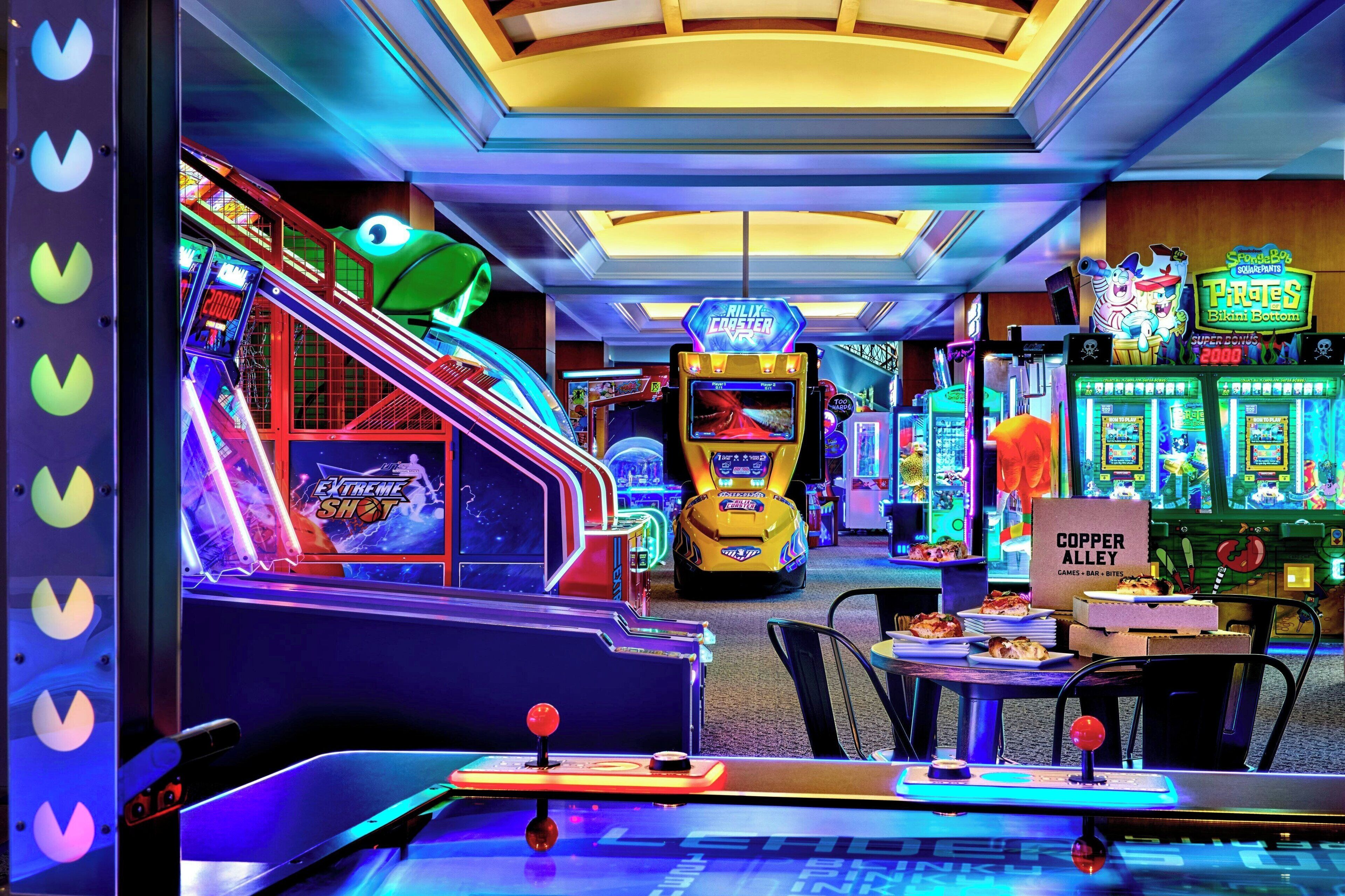 Een indoor speelhal met diverse spelautomaten, waaronder een 'Rilix Coster' en 'Extreme Shot' spel.
