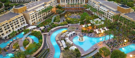 Een resort met meerdere zwembaden, een centrale binnenplaats en omliggende gebouwen.