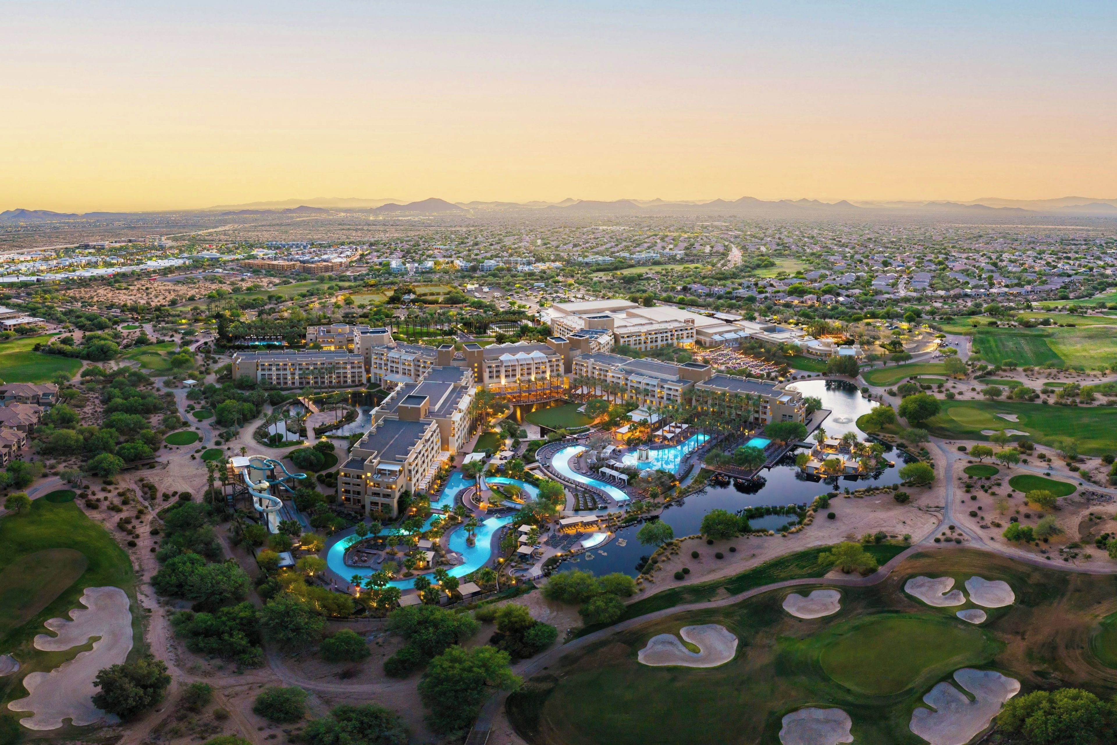 A resort with multiple buildings, a central pool area, and surrounding golf courses.