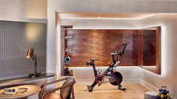 Une salle de sport moderne pour la maison, équipée d’un vélo d’appartement, d’un panneau mural en bois et de matériel d’exercice.