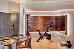 A modern home gym with a stationary bike, a wooden wall panel, and exercise equipment.