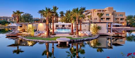 A resort with a pool, outdoor seating, and palm trees.