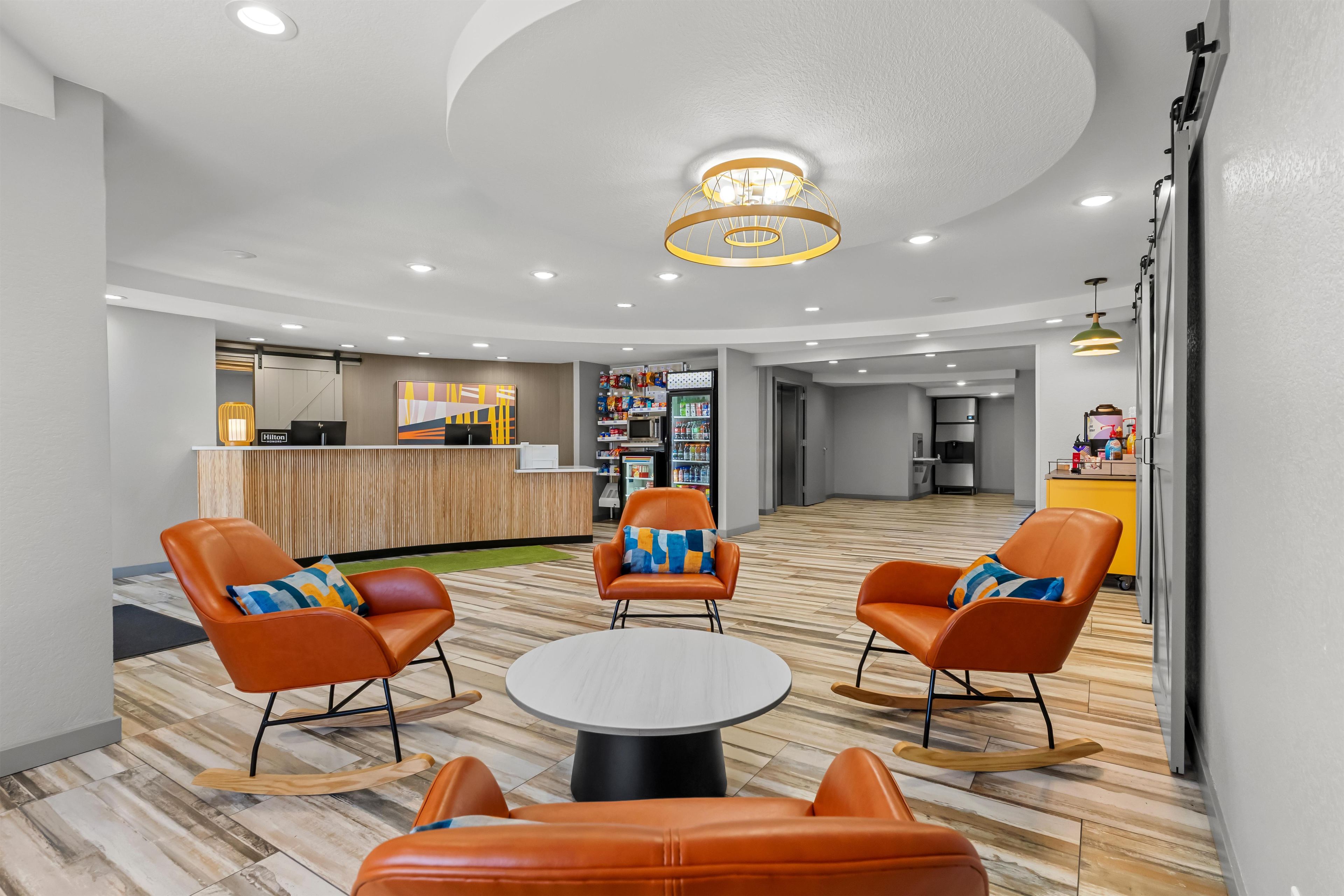 A hotel lobby with seating, a reception desk, and a kitchenette area.