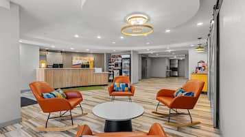 A hotel lobby with seating, a reception desk, and a kitchenette area.