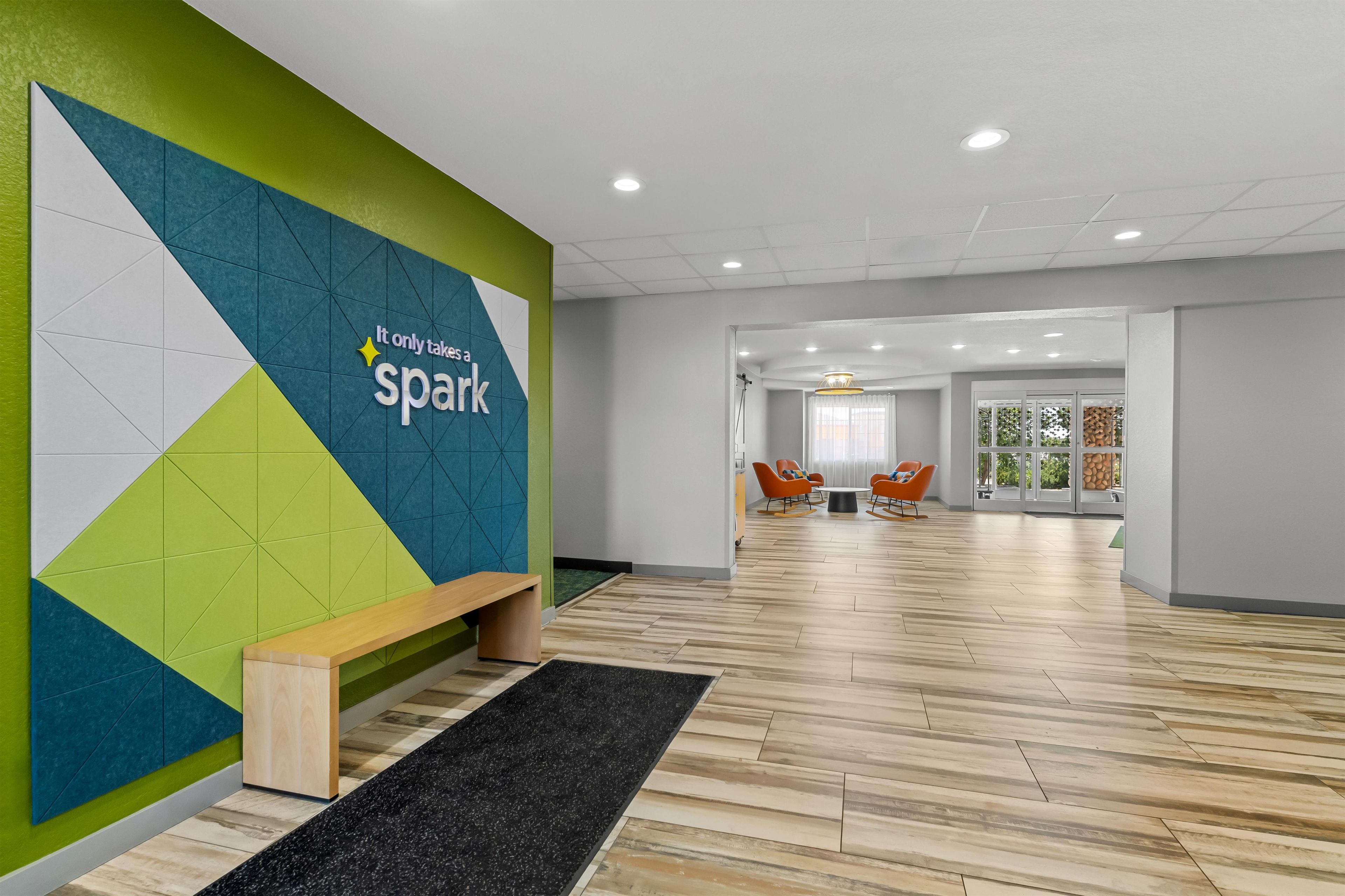 A modern interior with a geometric wall design, a wooden bench, and a herringbone floor pattern.