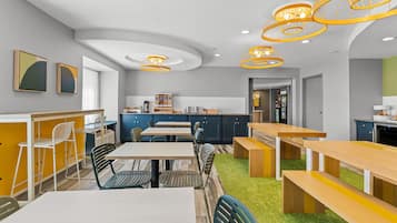 A modern kitchen with a central island, built-in appliances, and a seating area with tables and chairs.