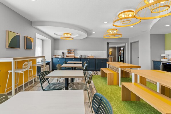 A modern kitchen with a central island, built-in appliances, and a seating area with tables and chairs.