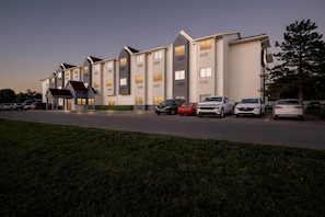 A multi-story hotel with a parking lot and a grassy area in front.