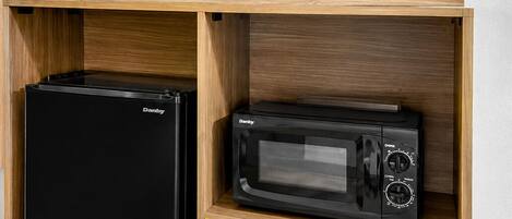 A compact kitchen unit with a refrigerator, microwave, and a flat-screen TV.