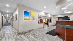 A hotel reception area with a reception desk, framed artwork on the walls, and a tiled floor. - Days Inn by Wyndham near Kansas Speedway (Kansas City)