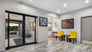 A hotel lobby with a modern design, featuring a wooden floor, glass doors, and framed pictures on the walls. - Days Inn by Wyndham near Kansas Speedway (Kansas City)