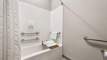 Un baño en esquina con una bañera blanca, un perchero y un estante con toallas dobladas.