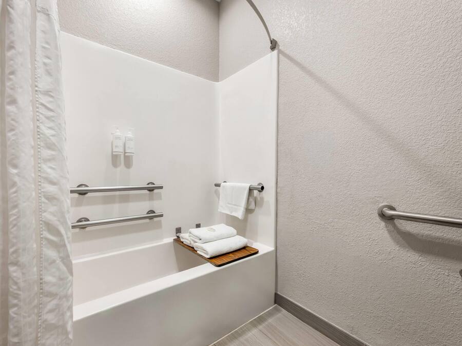 Un baño en esquina con una bañera blanca, un perchero y un estante con toallas dobladas.