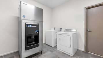Una lavandería compacta con dispensador de agua, lavadora y secadora.