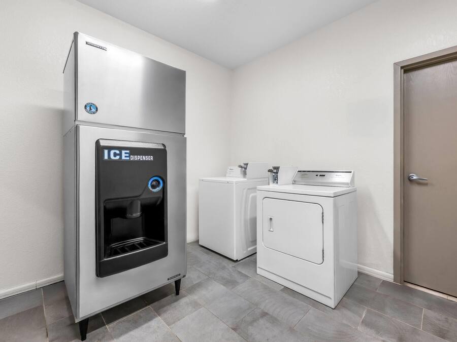 Una lavandería compacta con dispensador de agua, lavadora y secadora.