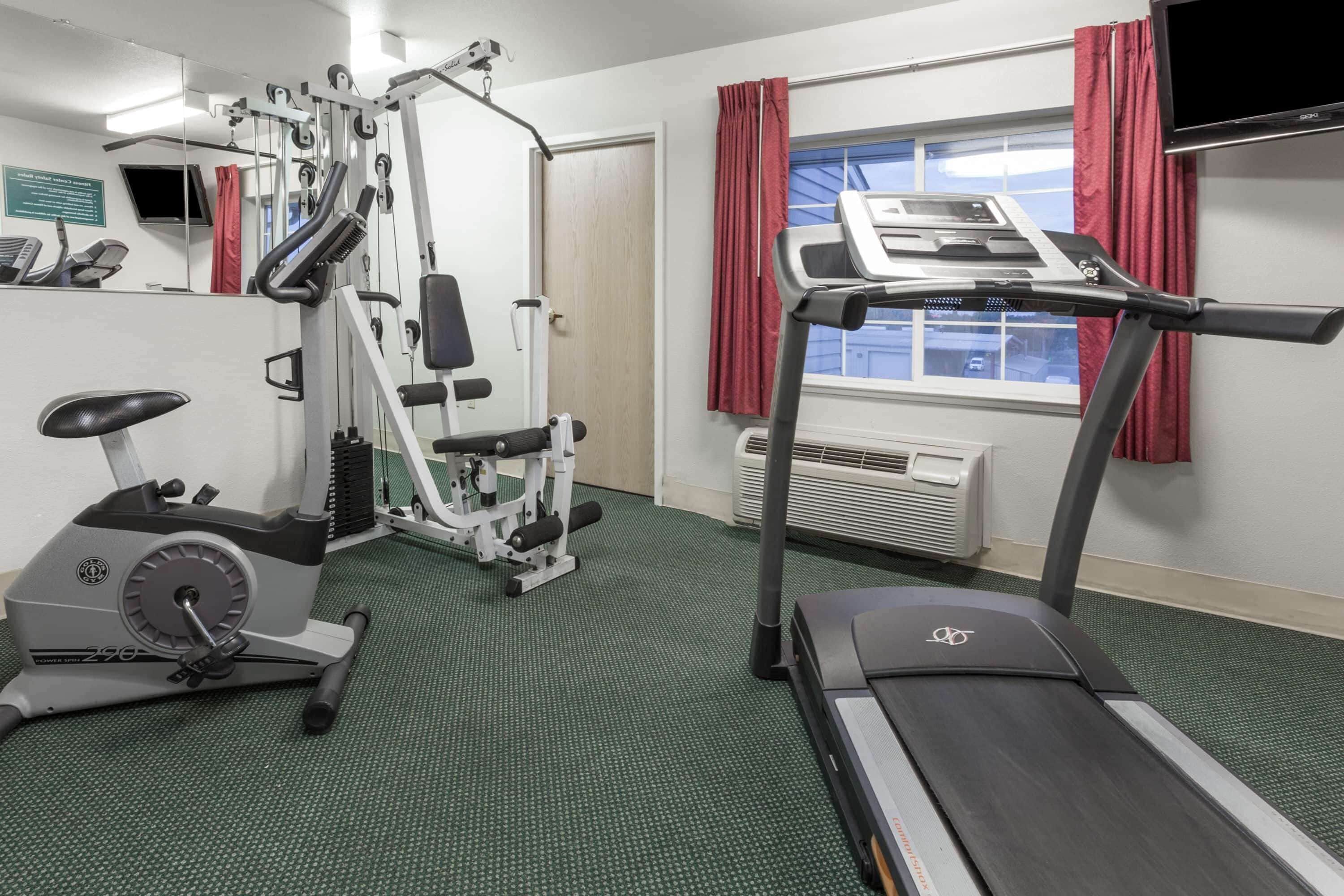 Un gimnasio con equipo cardiovascular, una cinta de correr y una bicicleta estática.