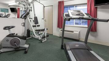 Un gimnasio con equipo cardiovascular, una cinta de correr y una bicicleta estática.