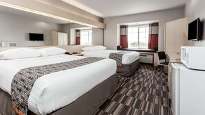 A hotel room with two beds, a desk, a television, and a microwave.