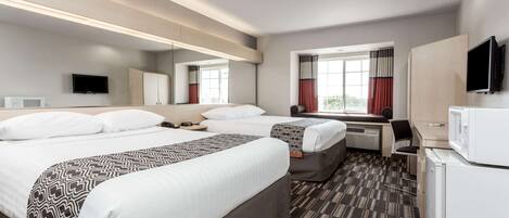 A hotel room with two beds, a desk, a television, and a microwave.