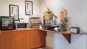 A kitchenette with a microwave, toaster, and coffee maker. There are also containers of grains and a hanging rack with utensils.
