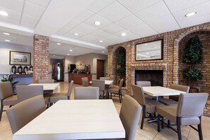 A restaurant with brick walls, multiple tables, and chairs. - Microtel Inn & Suites by Wyndham Lady Lake/The Villages (Lady Lake)