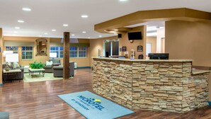 Un espace d’accueil doté d’un comptoir en pierre, de sièges et d’un tapis bleu orné du nom de l’hôtel.