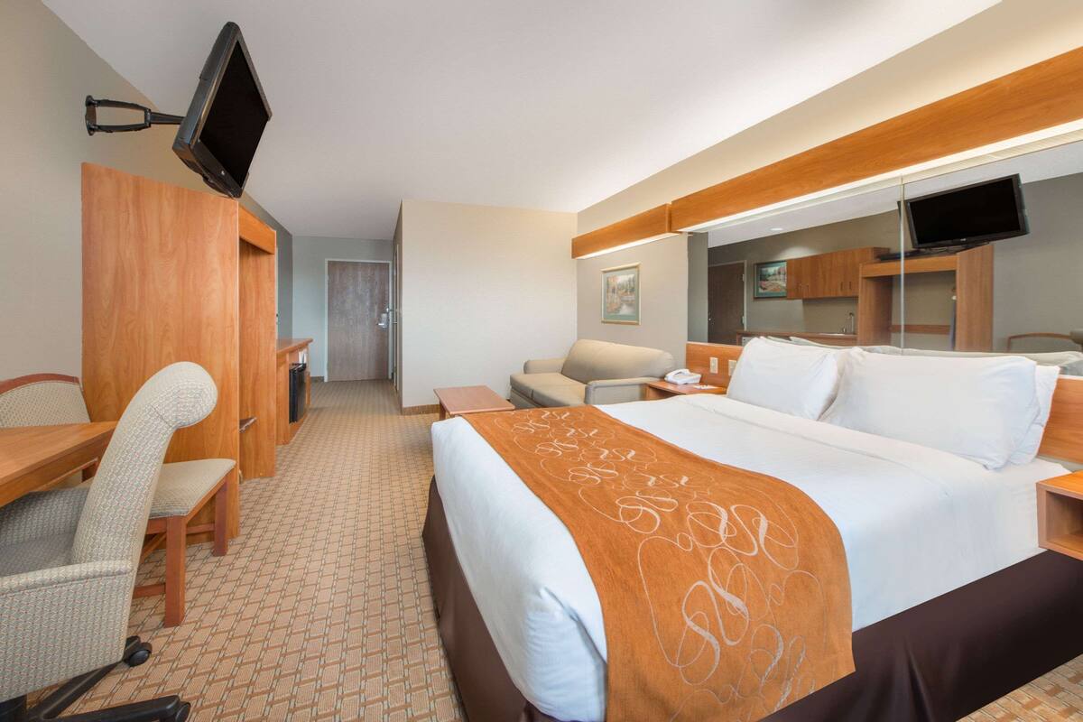 A hotel room with a bed, a desk, a chair, a television, and a bathroom.