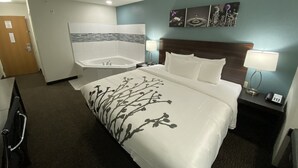 A hotel room with a large bed, a bathroom with a bathtub, and a wall-mounted artwork. - Sleep Inn St. Robert-Fort Leonard Wood (St. Robert)