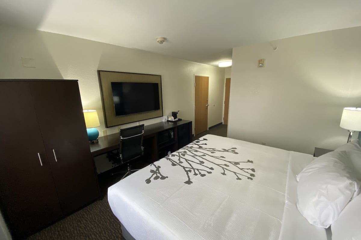A hotel room with a bed, a TV, a desk, and a wardrobe.