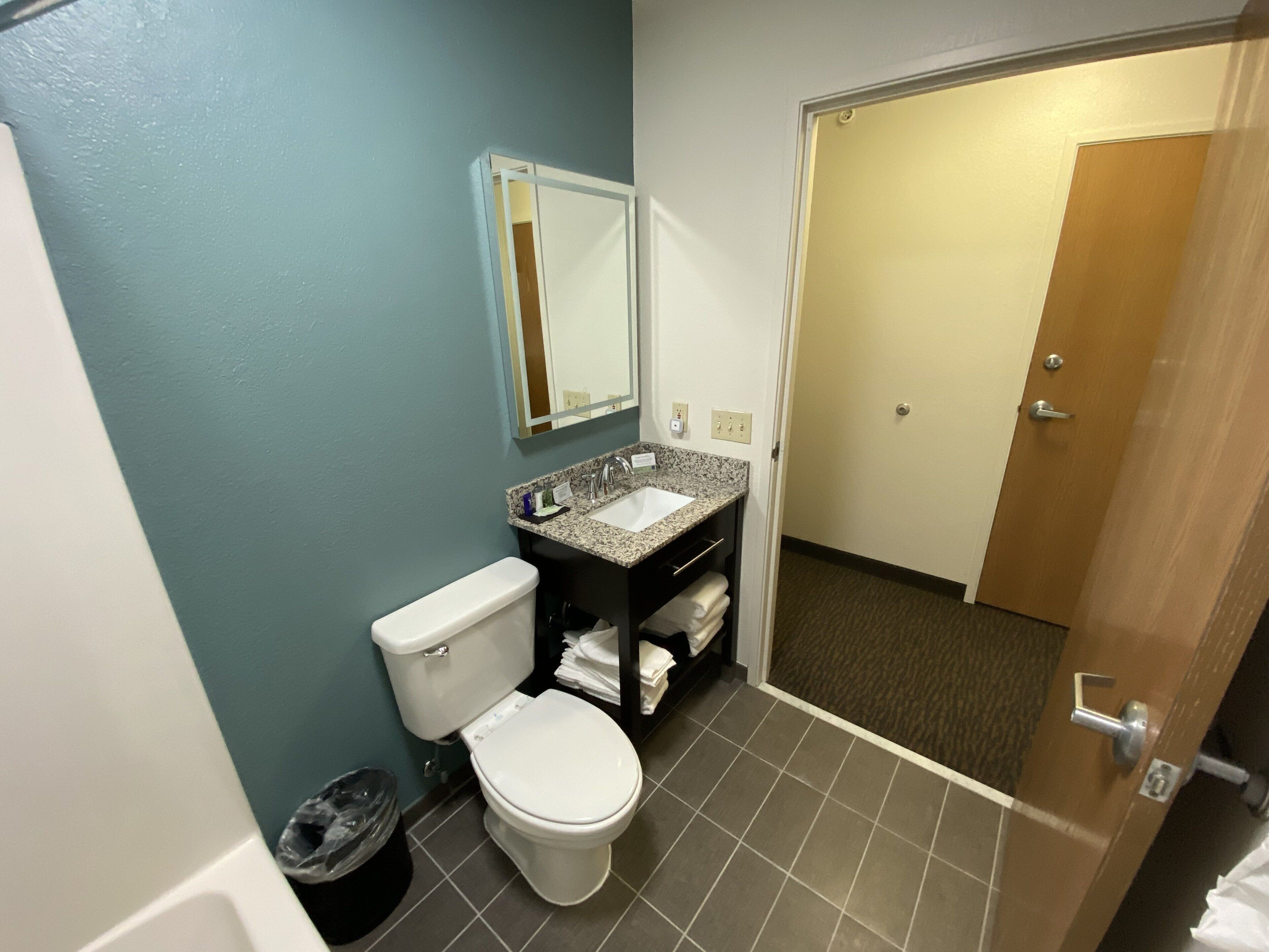 Een badkamer met toilet, wastafel en spiegel.