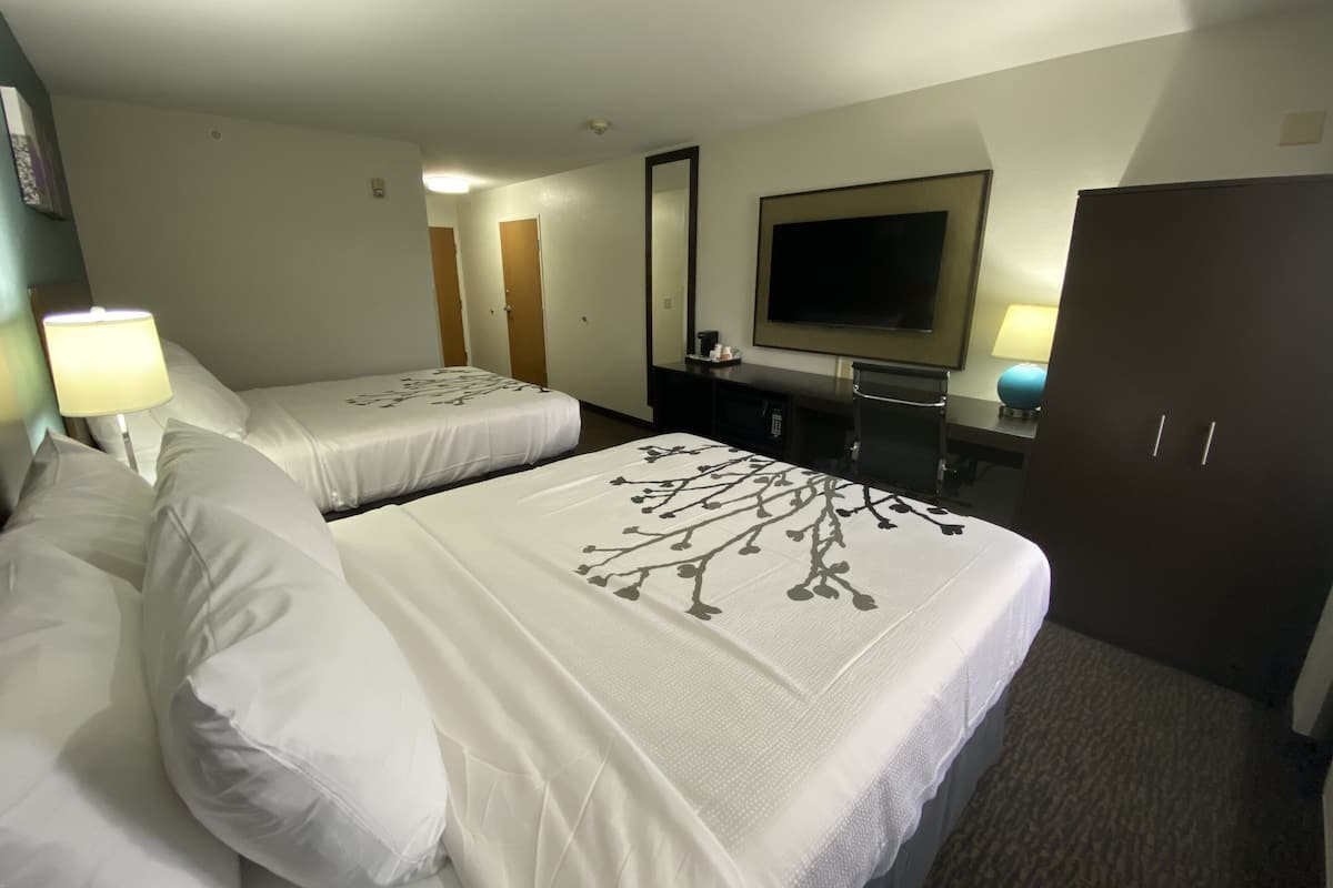 A hotel room with two beds, a TV, a desk, and a wardrobe.