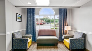 Une chambre d’hôtel avec une grande fenêtre, un lit, deux fauteuils et une lampe.
