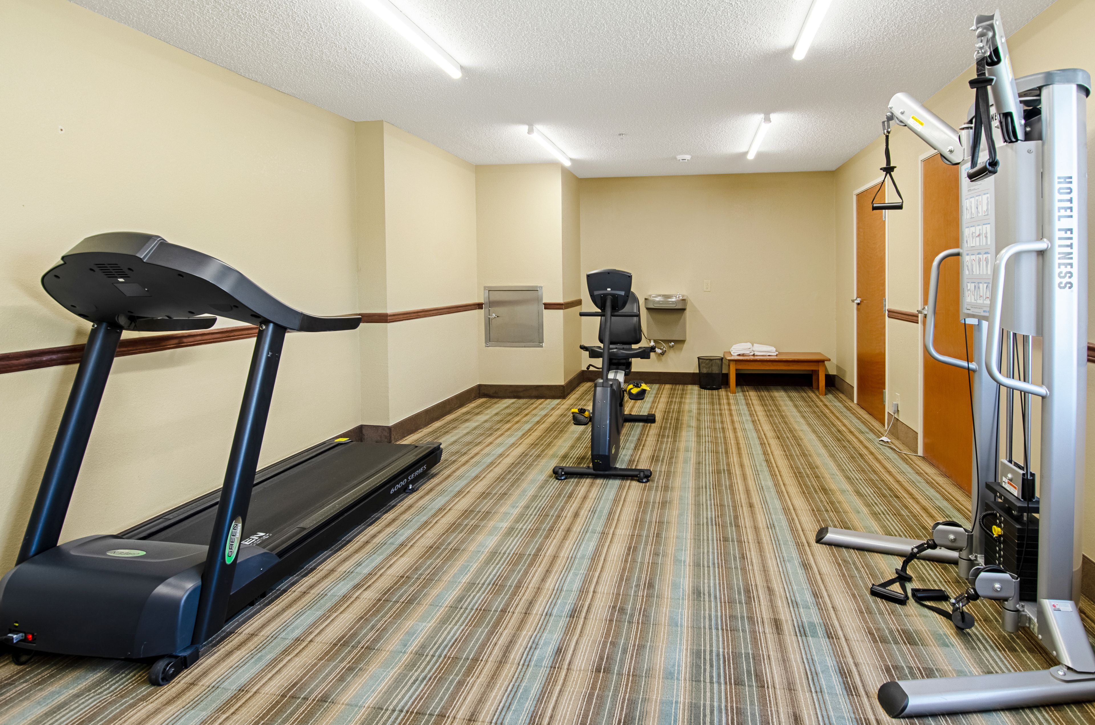 A hotel fitness center with a treadmill, stationary bike, and weight machine.