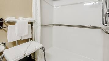 A white, modern bathroom with a shower, a bench, and a towel rack.