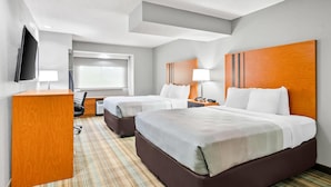 Une chambre d’hôtel avec deux lits, un bureau, une chaise, une télévision et une fenêtre.