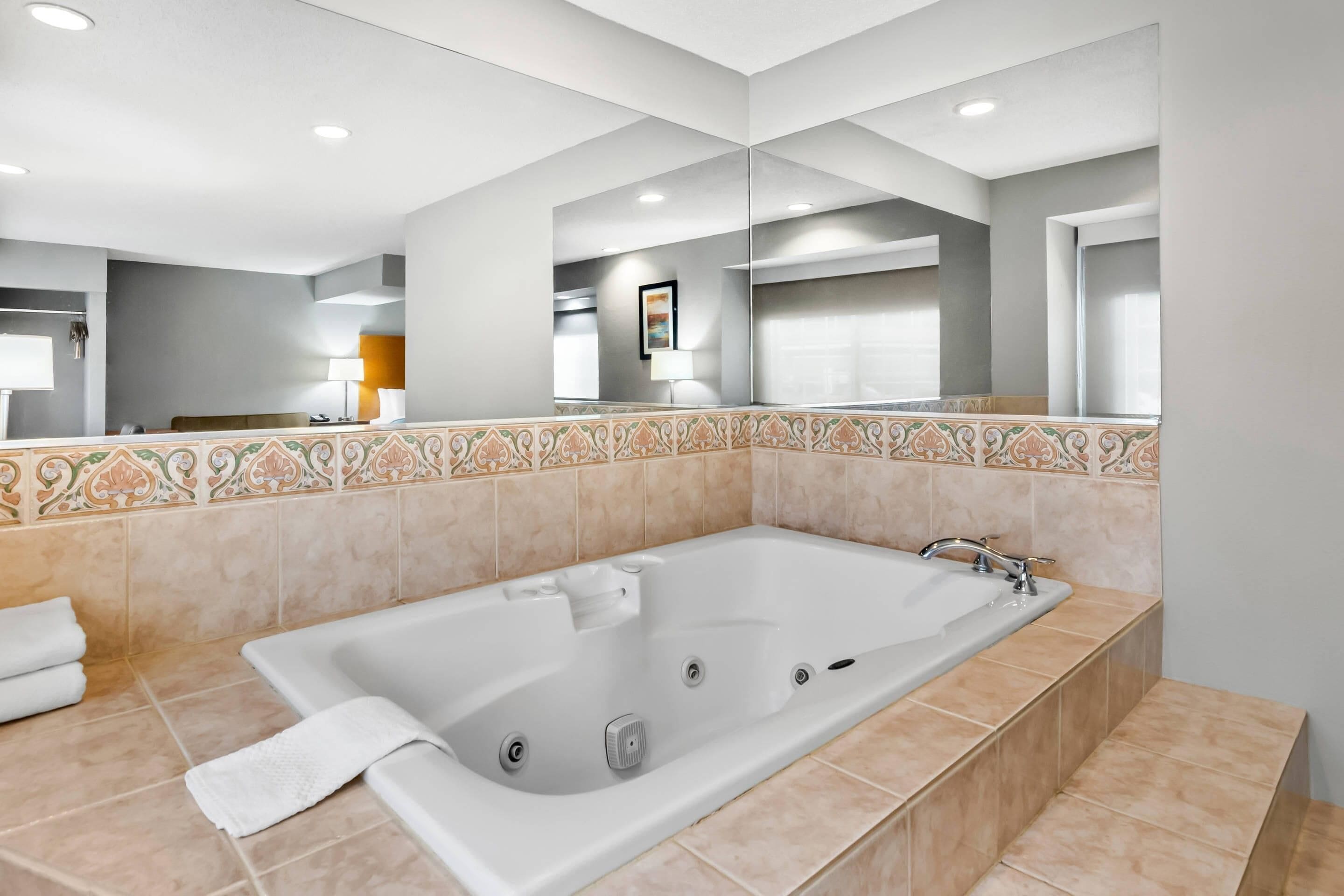 A modern bathroom with a large bathtub, a mirror, and a tiled backsplash.