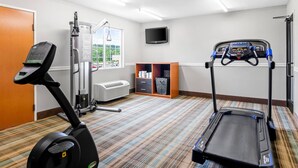 Une salle de sport équipée de matériel d’exercice, d’un téléviseur et d’une fenêtre donnant sur un beau paysage.