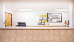 A reception desk with a tiled wall, framed certificates, and an American flag. - Super 8 by Wyndham Monmouth IL (Monmouth)